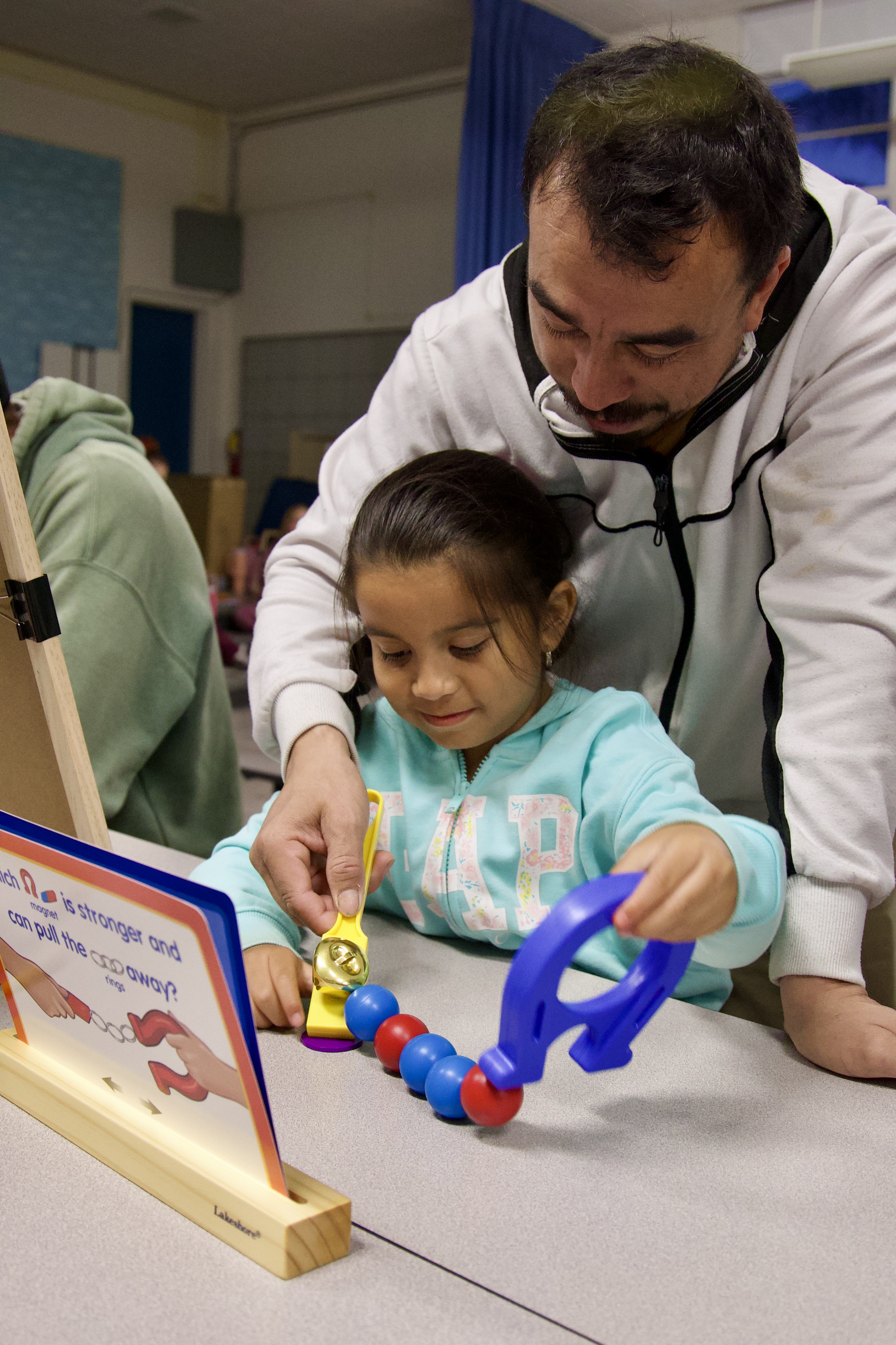A parent helping their child with their physics kit at the Oceano Family STEAM Night