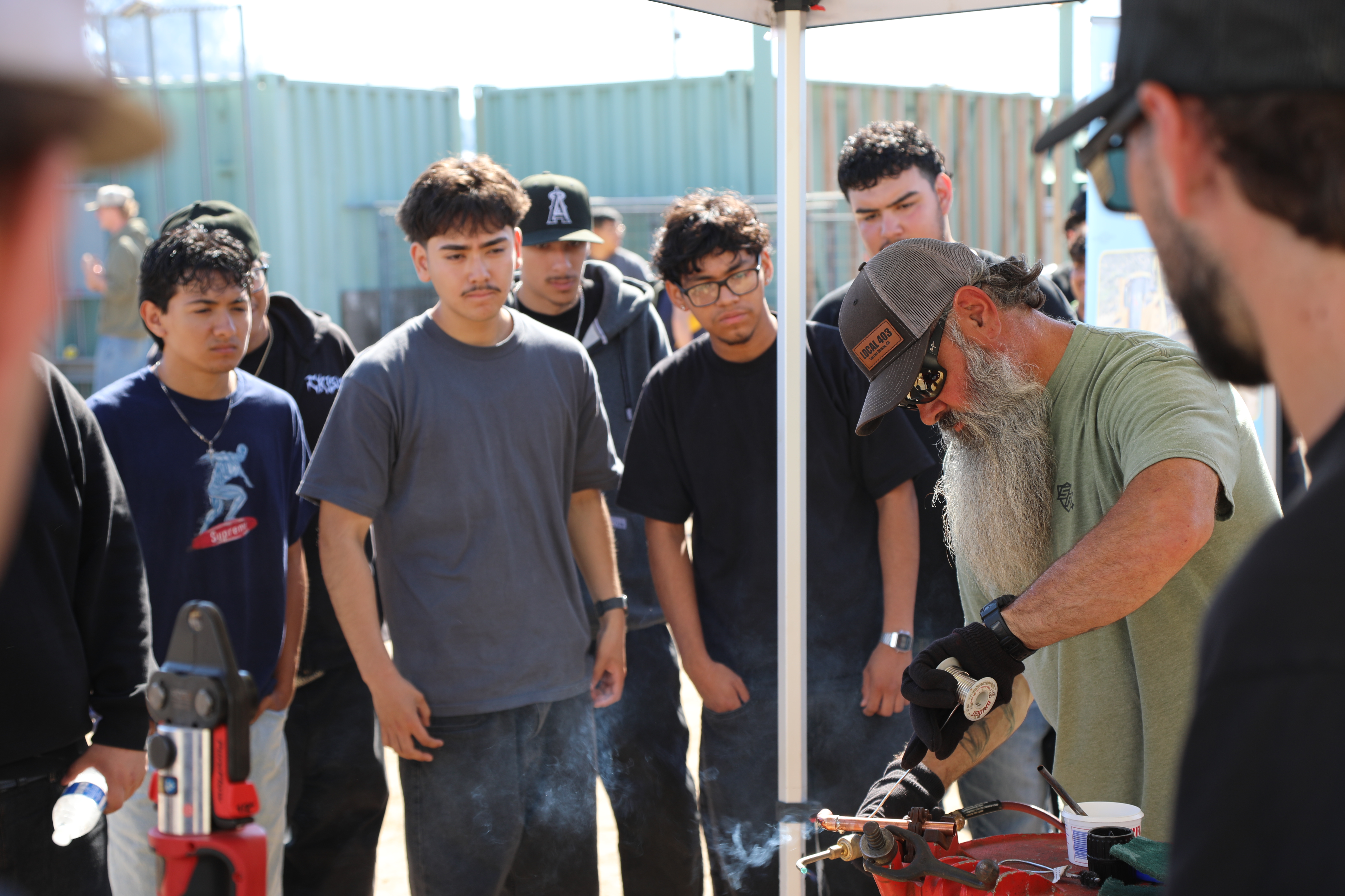 Students watching a pipe soldering demonstration during the Construction Trades Job Fair.